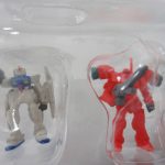 ブリスターに入った小型のモビルスーツ。白い機体と赤い機体が並ぶ。