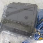 灰色の大型装備パーツと機体。袋に入った状態。