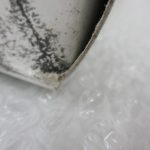 箱の角のクローズアップ。黒い点状の汚れが広がっている。