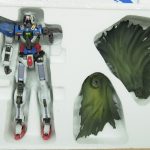 緩衝材に収まった本体と、緑色のマントのパーツ。