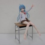 本体を机の形の台座に座らせた全身。手を挙げた姿勢。