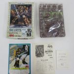 外箱と袋に入った茶色のランナー、カード、組立説明書を並べて撮影。説明書に SKURTS の印字があります。