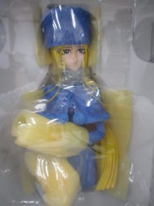 箱の中の本体の上半身。青い帽子と服、金色の長い髪の造形です。