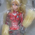 箱の中の本体の上半身。赤い服と金色の髪の造形です。