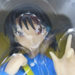 窓越しに撮影した黒髪の本体の上半身。青い上着と黄色いかばんの紐の造形です。
