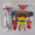 袋に入った本体を正面から撮影。赤と黄色の胴体に、斧状の武器が同梱されています。