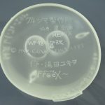 透明な台座パーツの裏の刻印。メーカー名と原型師名が入っています。