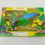 外箱の正面。窓からケイブラファエロと翼竜のフィギュアが見え、TURTLESのロゴ