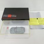 黒い外箱とクリアケースに入ったグリーンのミニカー、黄色い注意書きの紙と保護シート