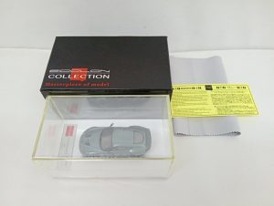 黒い外箱とクリアケースに入ったグリーンのミニカー、黄色い注意書きの紙と保護シート