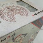 外箱の角のアップ。天面の紋章の図柄と側面のイラストの境目が写っています。