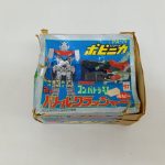 箱のふたの正面。『PA-79』『ポピニカ シリーズ』『バトルクラッシャー』の印刷と機体の絵。角に破れ