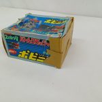 箱を斜め上から写したもの。ふたの絵柄と側面の商品名の帯