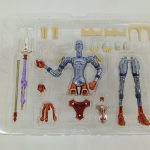 透明トレイに入った銀色の素体、槍のような長いパーツ、赤い装甲パーツ。