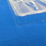 青い布の上に置いた、部品の入っていない空の透明トレイ