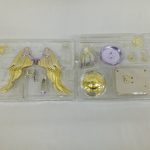 透明トレイ2枚。金色の翼の部品、紫の円盤、金色の円盤、白い台座
