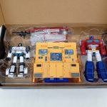 外箱のふたを開けた状態。透明トレイに入った3体のロボットと黄色い基地が収まっています。