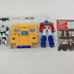 透明トレイに入った内容物を上から撮った写真。白いロボット、黄色い基地、赤いロボット、台紙が並んでいます。