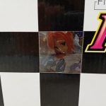 外箱正面の窓のアップ。中のフィギュアの頭部と赤茶色の髪が写っています。