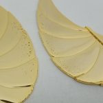 金色の翼のパーツ2枚を寄せて撮った写真。表面に細かい点状の跡があります。