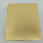 金色の箱の表面。押し型の模様と文字が入っています。