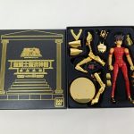 開いた黒い箱。金色のパーツと赤い服のフィギュア本体が収まっています。