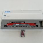 ケースのふたを開けた状態。中の車両と、手前に小さな部品の袋が置かれています。