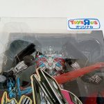 外箱正面の窓のアップ。黒いロボット本体と赤い刀身の剣、左上にトイザらスのシール。