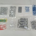 袋に入ったランナー（部品の枝）を並べたもの。灰色・青・黄・赤・白の部品