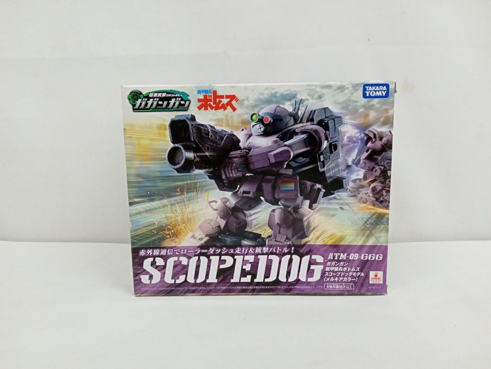外箱の正面。紫色のロボットの絵と「SCOPEDOG」「ATM-09-GGG」の文字、「ガガンガン」「ボトムズ」のロゴが印刷されています。