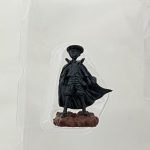 付属の小さな人形。黒いマントに笠をかぶった姿で、岩の台座に立っている