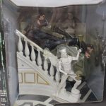 外箱の正面。階段の上で戦う人形と白い石像のジオラマが窓越しに見えます。