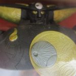 窓越しに撮影した本体の頭部と胸。黒い装甲と金色の三日月の造形です。