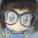 窓越しに顔のアップを撮影。大きな黒縁メガネをかけています。