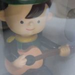 窓越しに撮影した緑の帽子の人形。ギターを抱えています。