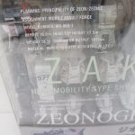 窓越しに撮影した白いパーツと機体の諸元の印字。