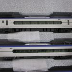 ケースの中の先頭車と中間車。白い車体に紫の帯です。