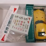 箱の中の拡大。TOYOTA 2000 GT MF10 の帯と、黄色いボディ、デカールがあります。