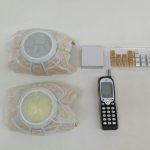 袋入りのパーツ2個と携帯電話、小物パーツ