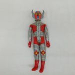 赤と銀のコスチュームを着た人形の全身正面。角の付いたヘルメットをかぶった姿