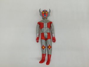 赤と銀のコスチュームを着た人形の全身正面。角の付いたヘルメットをかぶった姿