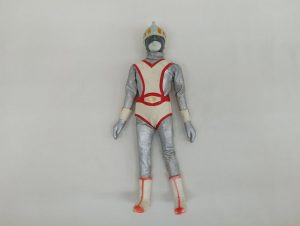 銀と白赤の衣装とヘルメットを着けた人形の全身を正面から写した写真