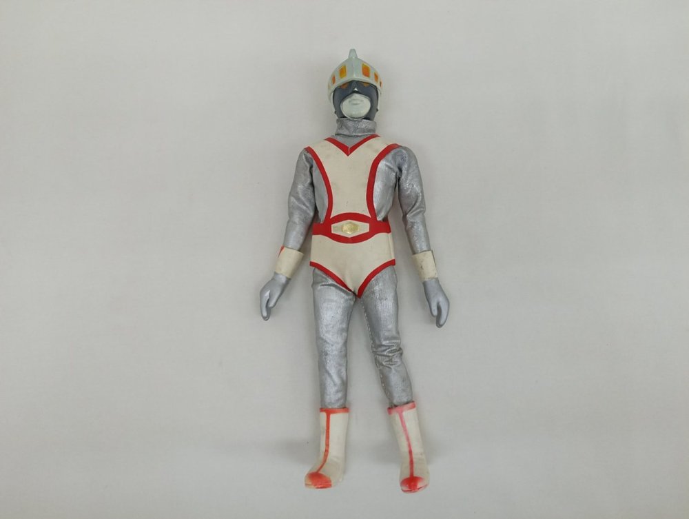 銀と白赤の衣装とヘルメットを着けた人形の全身を正面から写した写真