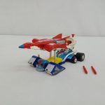 本体を斜め前から写した様子。青いレーシングカーの上に赤い機体が載り、手前に赤いミサイル2本が置かれています。