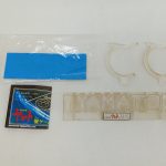 付属品を並べた写真。青い台紙、小さな箱、透明なパーツ、「YAMATO」の透明な部品が写っています。