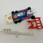 組み立てた青い車体と、別に置かれた赤いウイングや銀色の細長い部品。