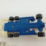 車体を裏返した底面。青いシャーシと4本のタイヤ、手前に銀色のネジが並んでいます。