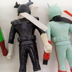 黒い人形と水色の人形の背面のアップ。白い帯と刻まれた文字