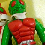 緑の頭と赤い胸の人形のアップ。白いマフラーとベルト