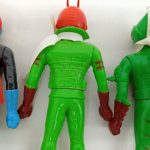 人形の背面のアップ。緑の体に刻まれた文字とマフラー